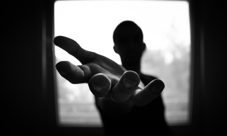 Black and white photo of a man holding his hand out