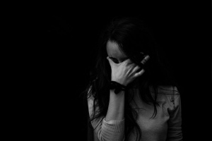 Woman crying covering her face with her hand. Black and white photo of woman. Long brown haired woman